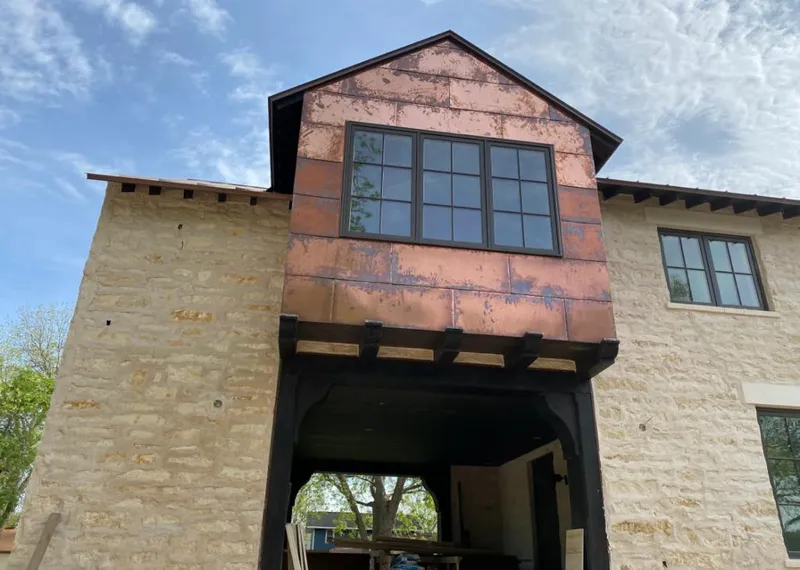 Copper metal panel facade on a stone building for Roof Repair in Williamson
